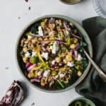 Bold and briny kale farro salad with chickpeas in a bowl with a fork.
