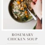 Rosemary chicken soup with kale and white beans, in a bowl and hand dunking fresh sourdough bread into the soup.
