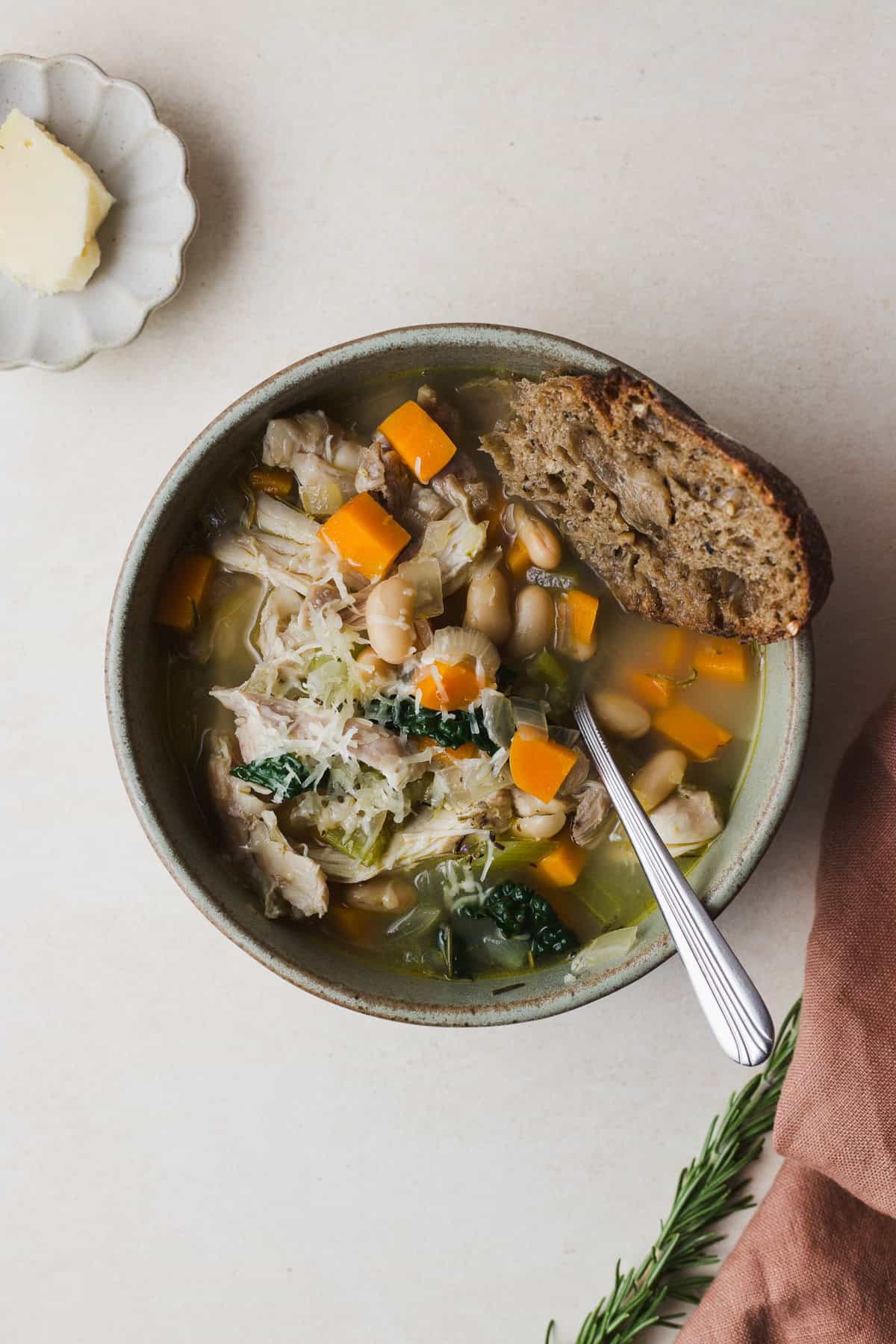 Bowl of rosemary chicken soup with white beans and kale.