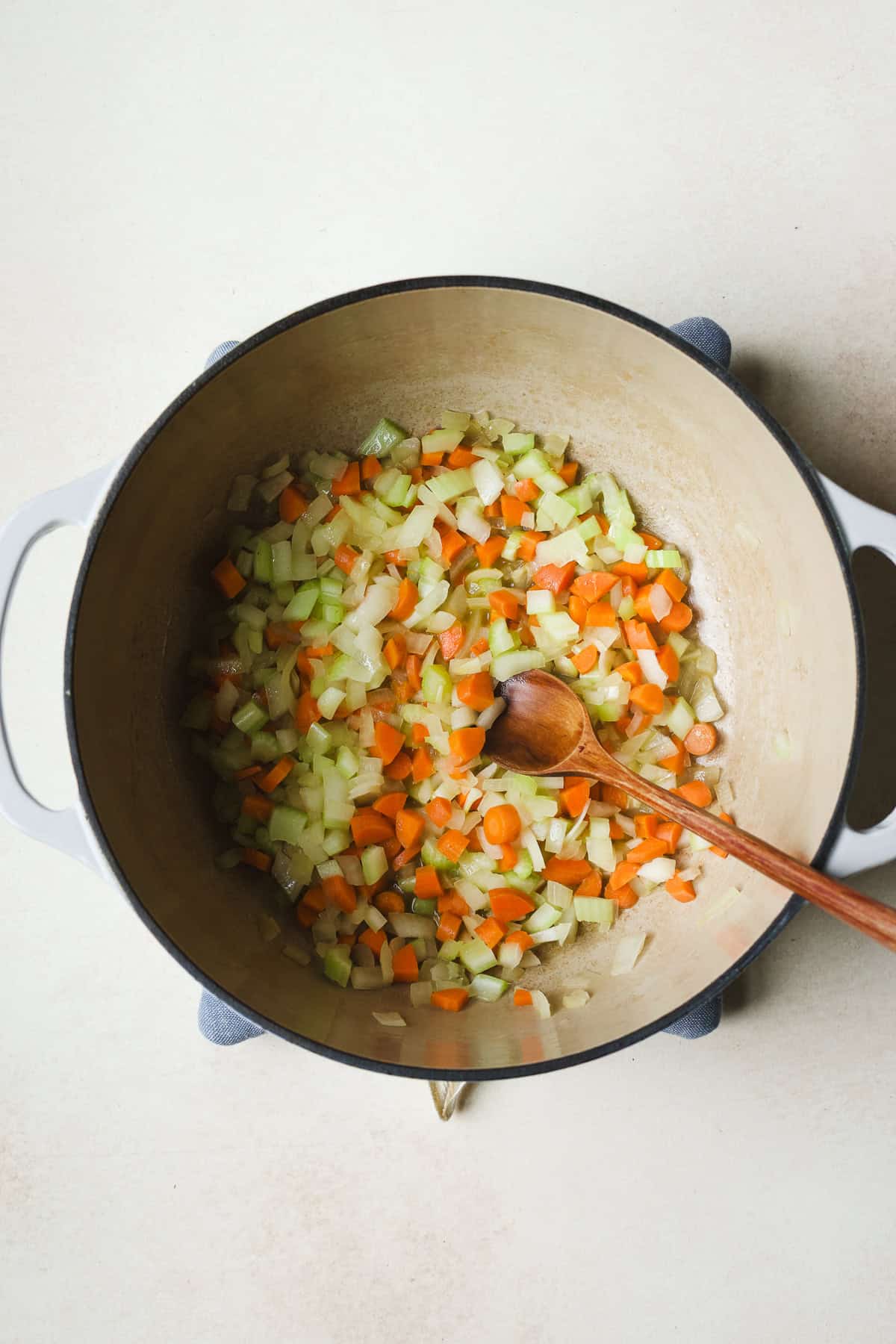 Sautéing onion, celery, and carrots in olive oil in a large soup pot.