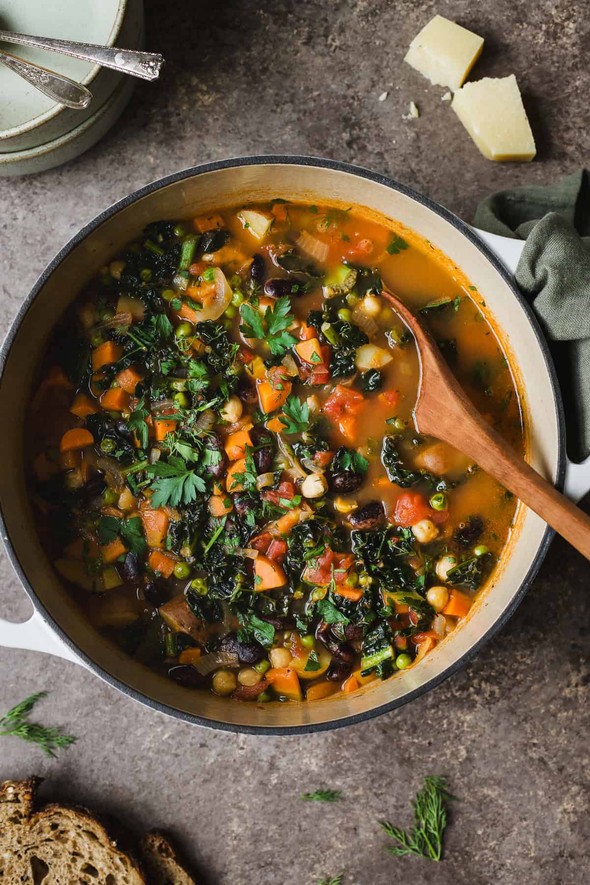 Large pot of spring minestrone soup with potatoes and fresh herbs.
