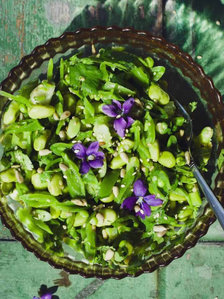 Snap pea and edamame salad in a bowl with fork.