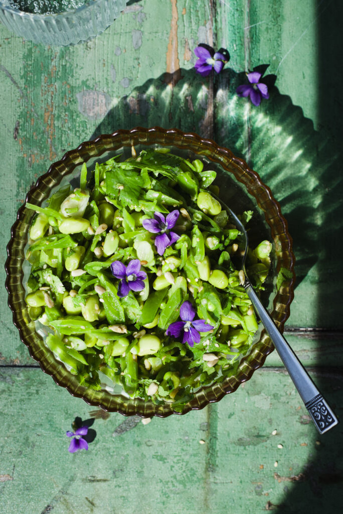 Snap pea and edamame salad in a bowl with fork.