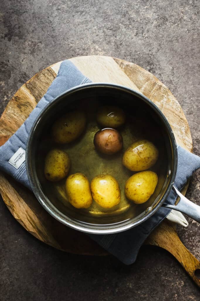 Small gold and red potatoes boiling in a small pot.