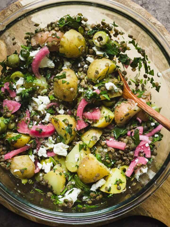 Warm lentil salad with feta and potatoes in a large bowl.