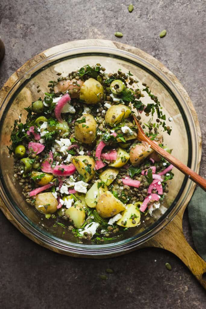 Warm lentil salad with feta and potatoes in a large bowl.