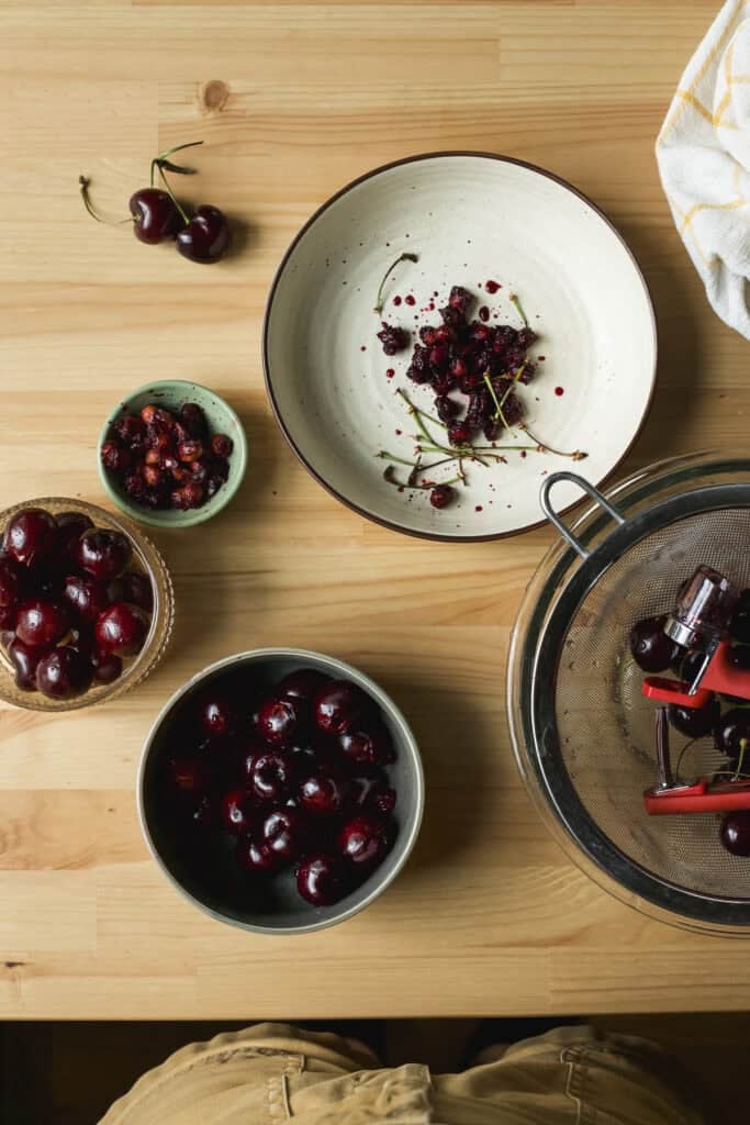 Sweet cherries being pitted with a handheld cherry pitter.