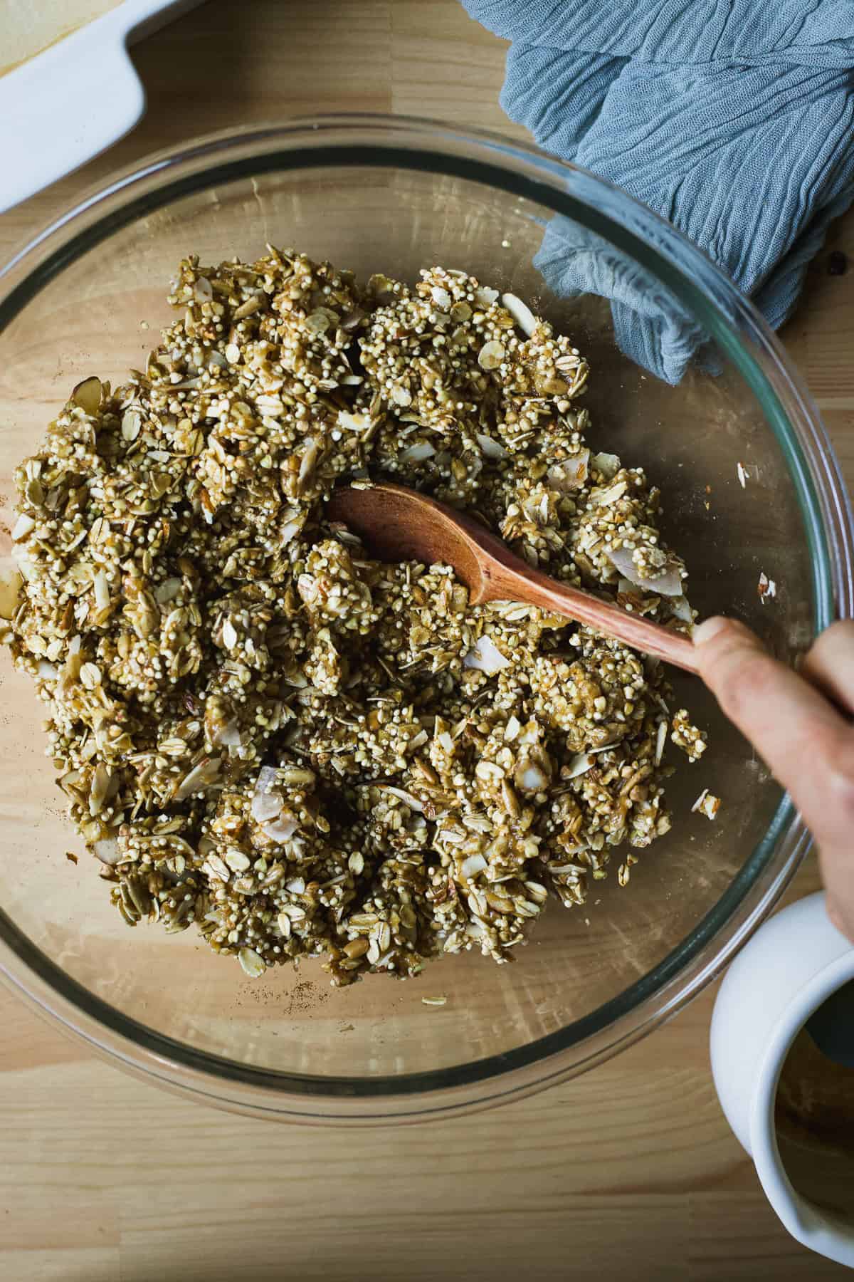 Stirring nut butter, honey, and granola mixture together in a bowl.