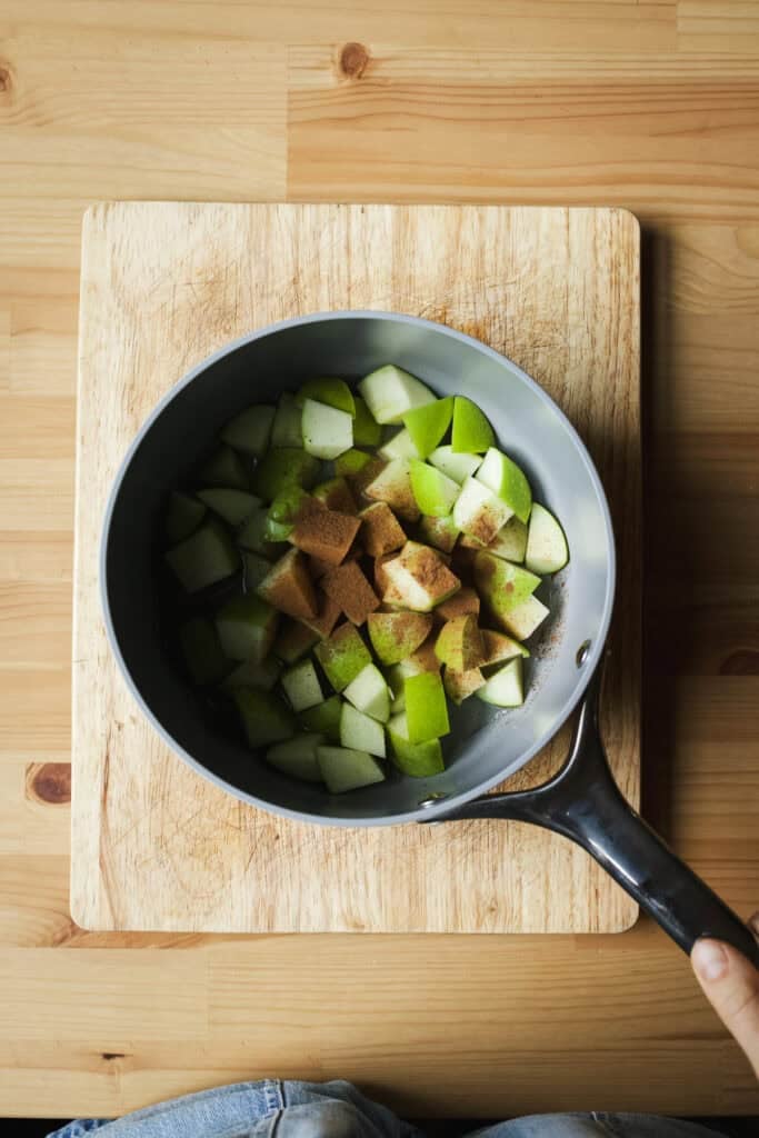 Apple chunks in a pot with cinnamon and cloves.