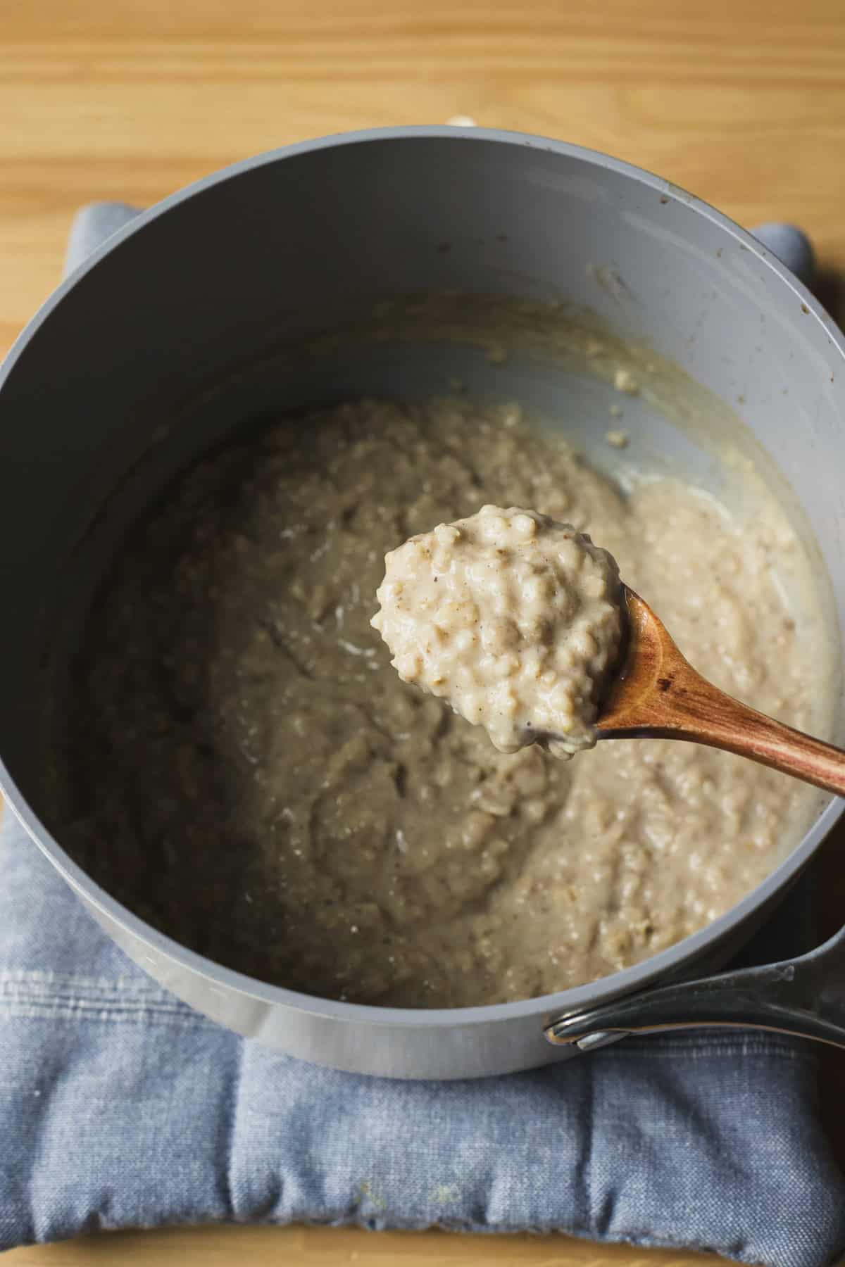 Spoonful of chai oats hovering over pot.