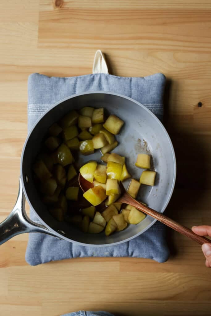 Stewed apples in a pot with a spoon.