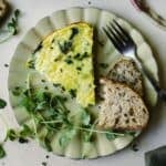 Frittata slice on a plate with toast and pea shoots.