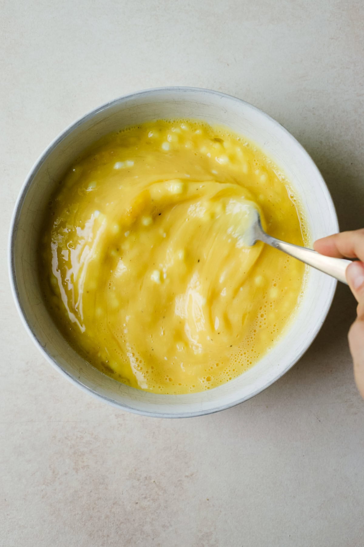 Whisking cottage cheese and eggs together in a bowl.