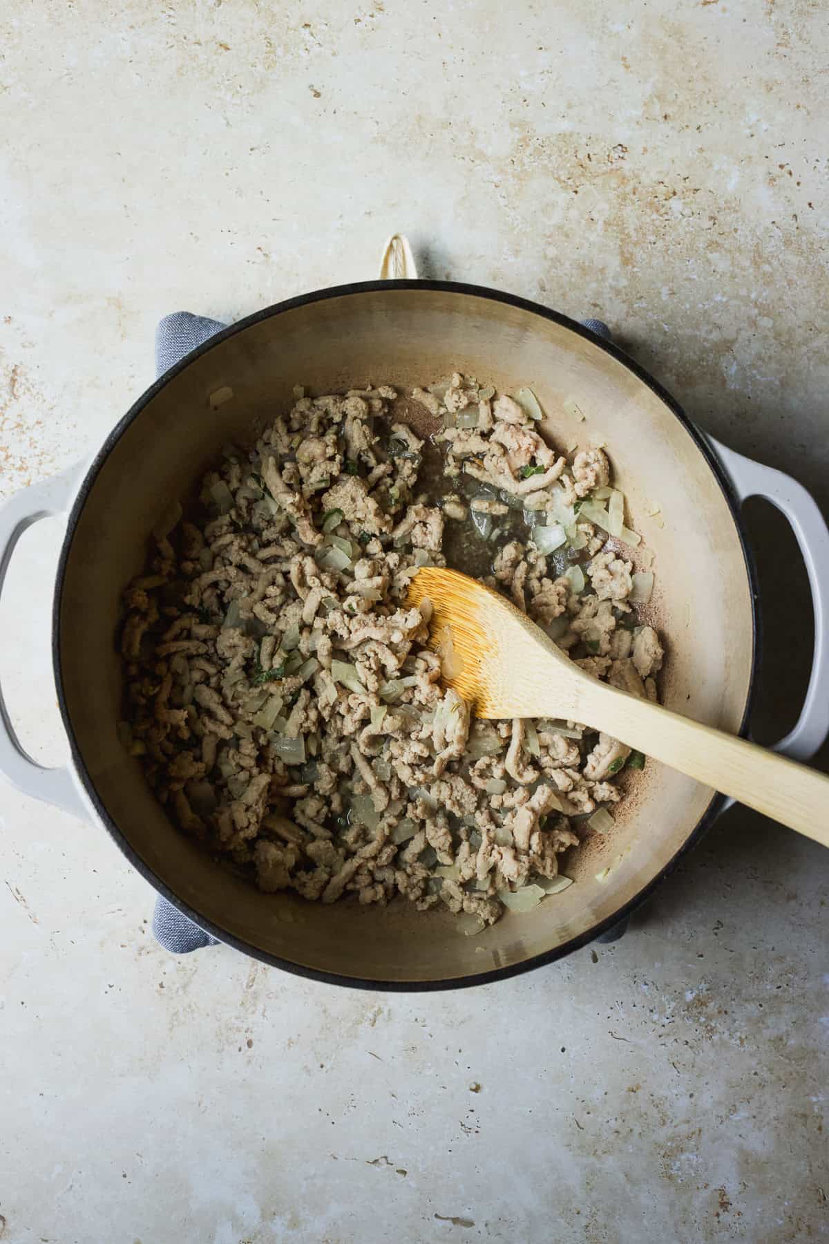 Sautéing ground chicken with aromatics in a dutch oven.